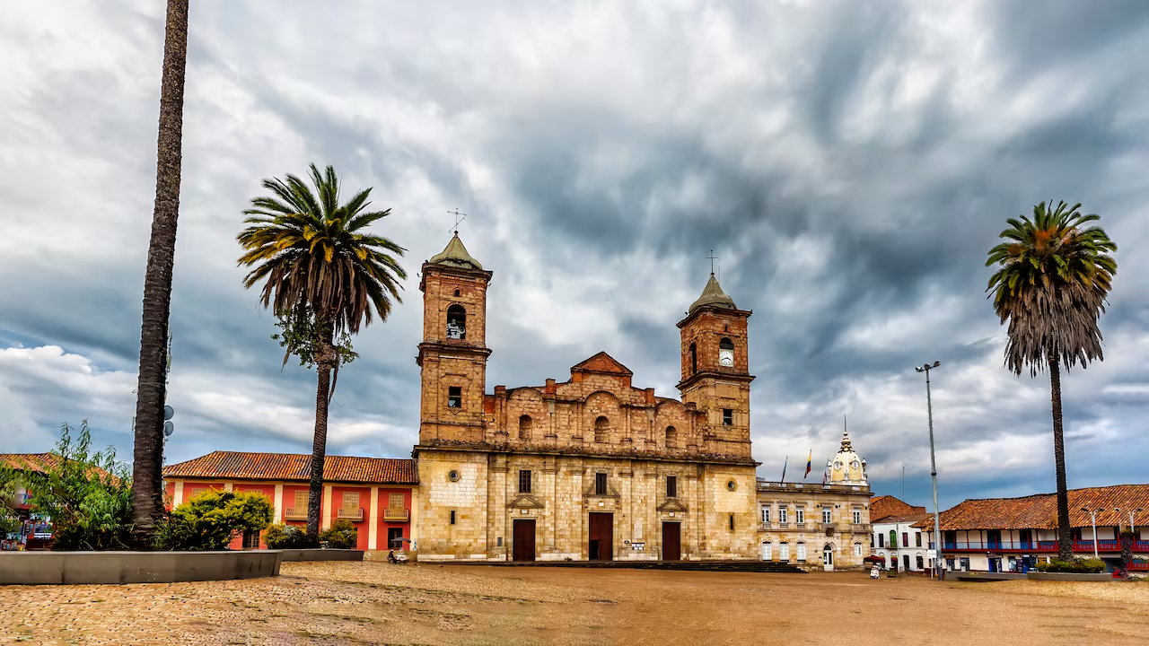Imagen del centro de Zipaquirá, Colombia, con la catedral de fondo y personas recorriendo sus calles empedradas.